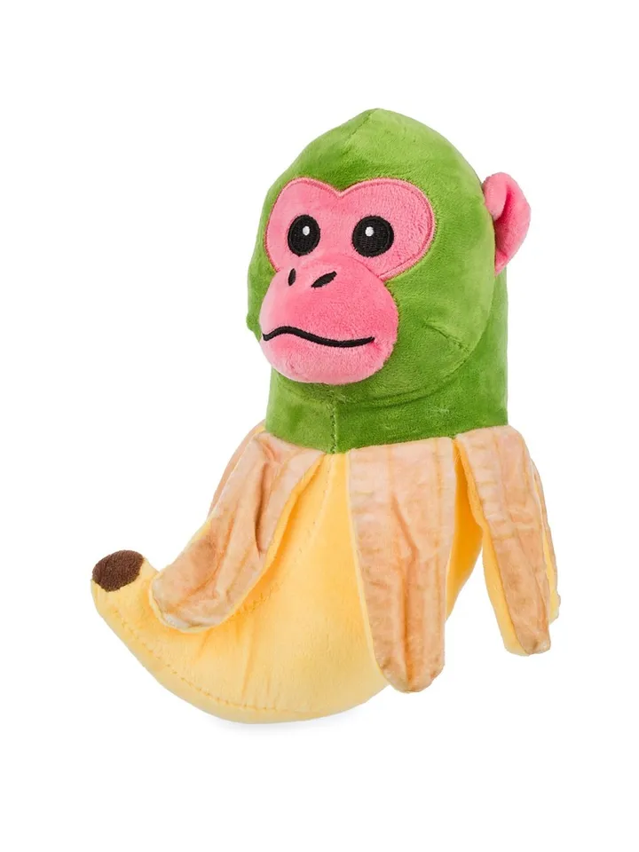 Zabawna pluszowa zielona małpka z różową buzią wyłaniająca się z obranego banana